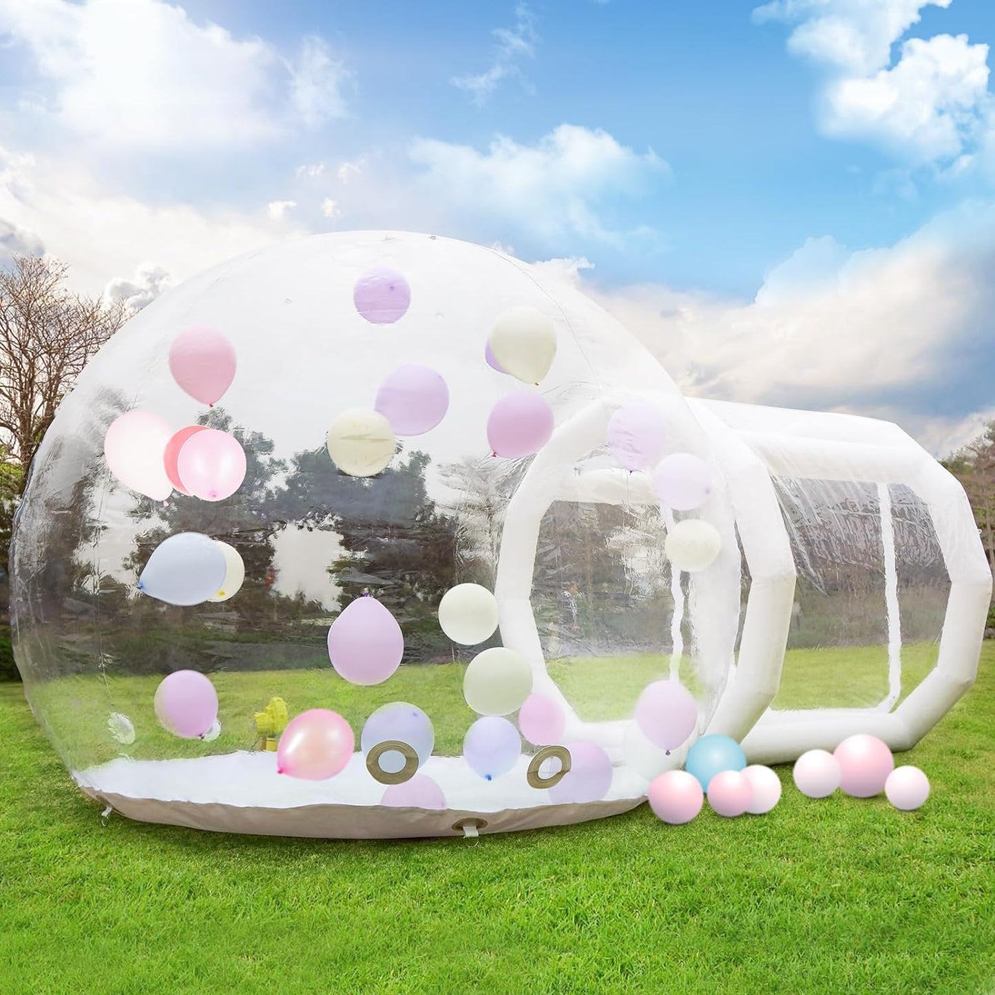 Inflatable transparent bubble dome filled with pastel balloons on green grass