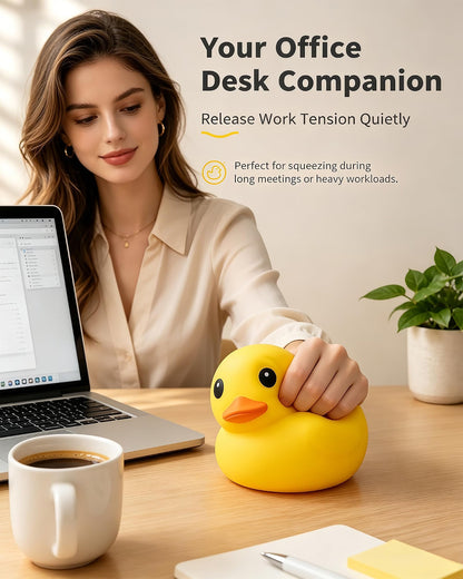 At her office desk, a woman squeezes the Giant Yellow Duck Squishy – a flour-filled TPR fidget and stress relief toy by Okie Soft Play, featuring bright yellow with hints of orange. Nearby rest a laptop, coffee cup, and plant. Calming navy blue decor accents complete the scene. Text reads: Your Office Desk Companion. Release Work Tension Quietly.