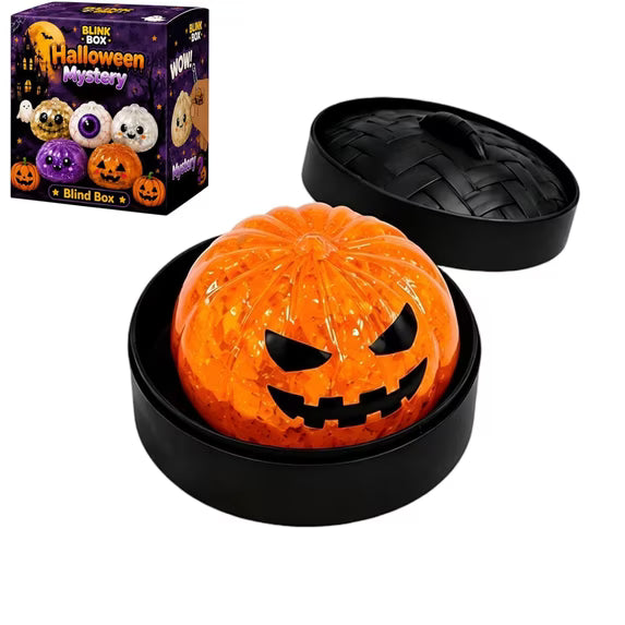 A round orange Halloween Bun Squishy Toy from Okie Soft Play, featuring a mischievous jack-o-lantern face, sits in a black container. In the top left corner, a Halloween Mystery Blind Box package is displayed.