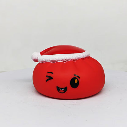 The Christmas Bun Squeaky Toy by Okie Soft Play is a red, round toy featuring a winking cartoon face and a Santa hat, designed to resemble a playful holiday bun. It is shown against a plain white background.