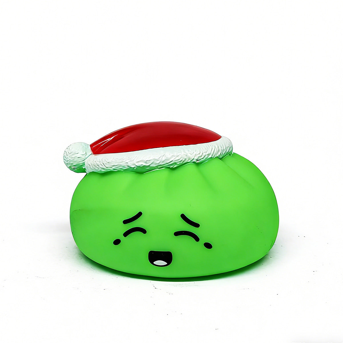 A green, round Christmas Bun Squeaky Toy by Okie Soft Play features a sad face and wears a festive red and white Santa hat, making it a cute holiday stocking stuffer. The plush toy sits on a plain white background.