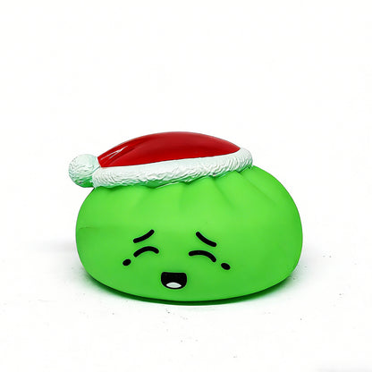 A green, round Christmas Bun Squeaky Toy by Okie Soft Play features a sad face and wears a festive red and white Santa hat, making it a cute holiday stocking stuffer. The plush toy sits on a plain white background.