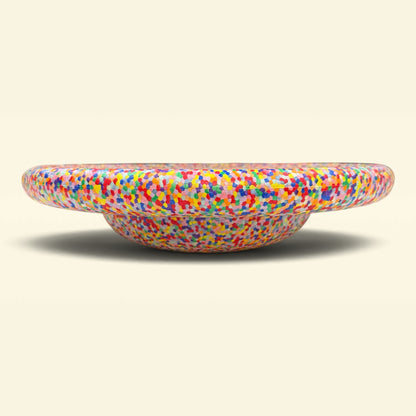 A shallow, round balance board with a wide rim, featuring a mosaic pattern of small, colorful squares on a neutral beige background. The Rainbow Balance Board for Kids by Okie Soft Play Store is designed for active play and wobble fun.